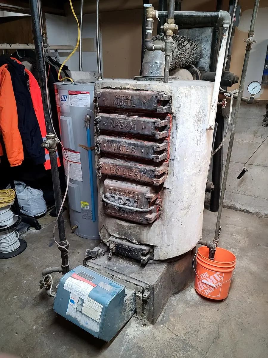 Old boiler wrapped in asbestos-containing insulation before removal in a Winnipeg mechanical room