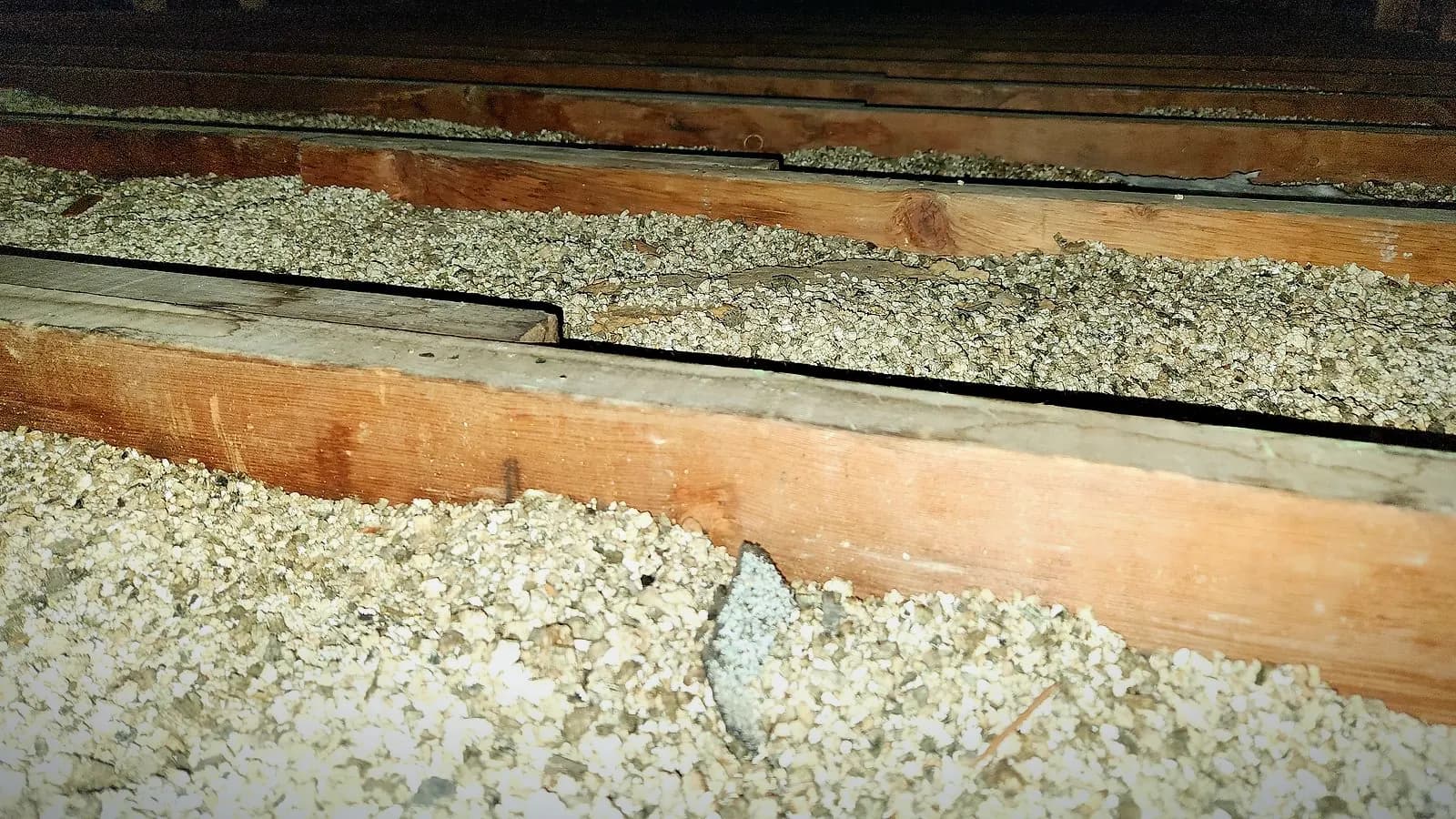 Loose vermiculite insulation filling the spaces between attic joists in an older Winnipeg home