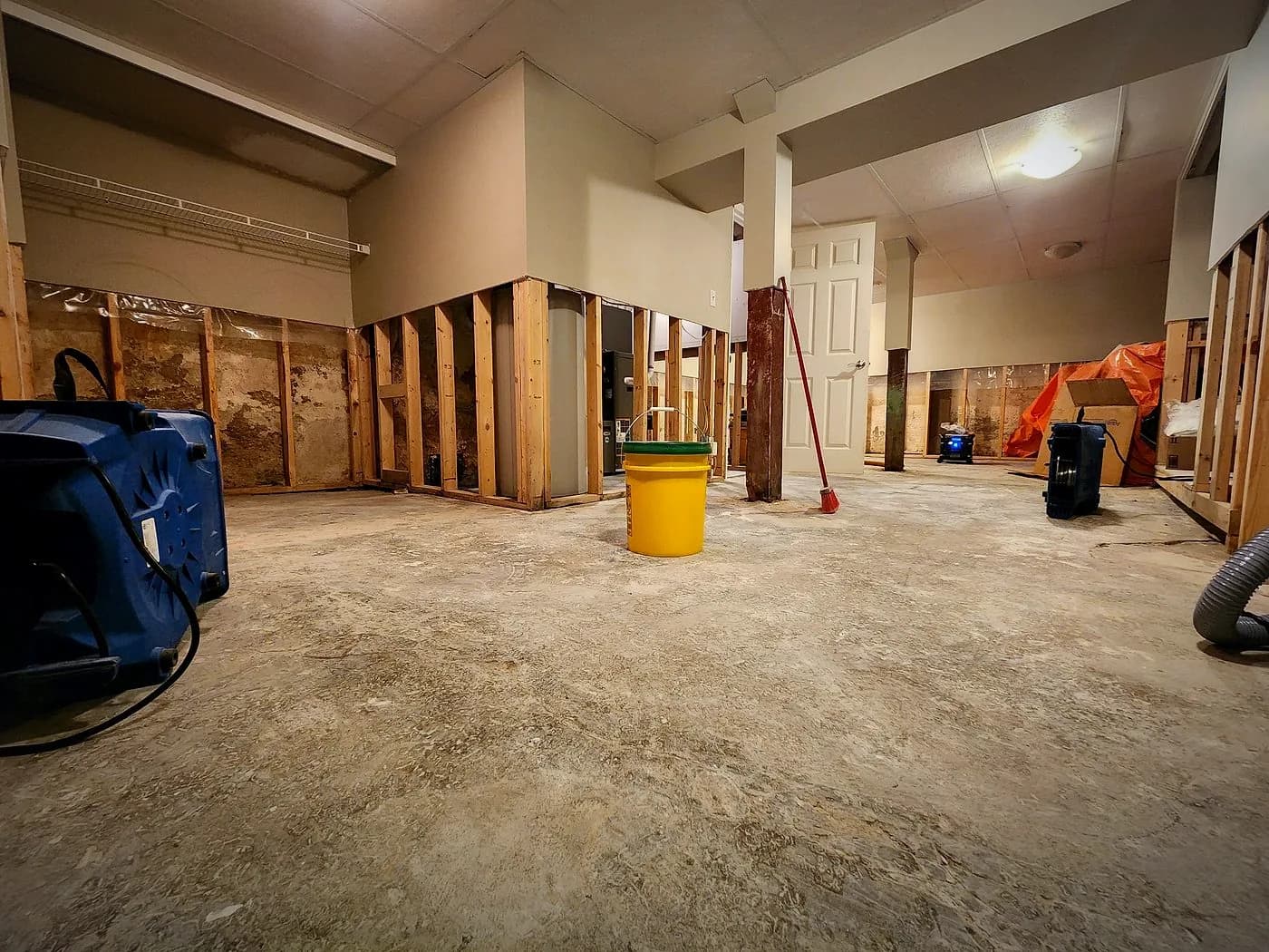 Winnipeg basement with flood cuts in the drywall and commercial air movers and dehumidifiers running during structural drying