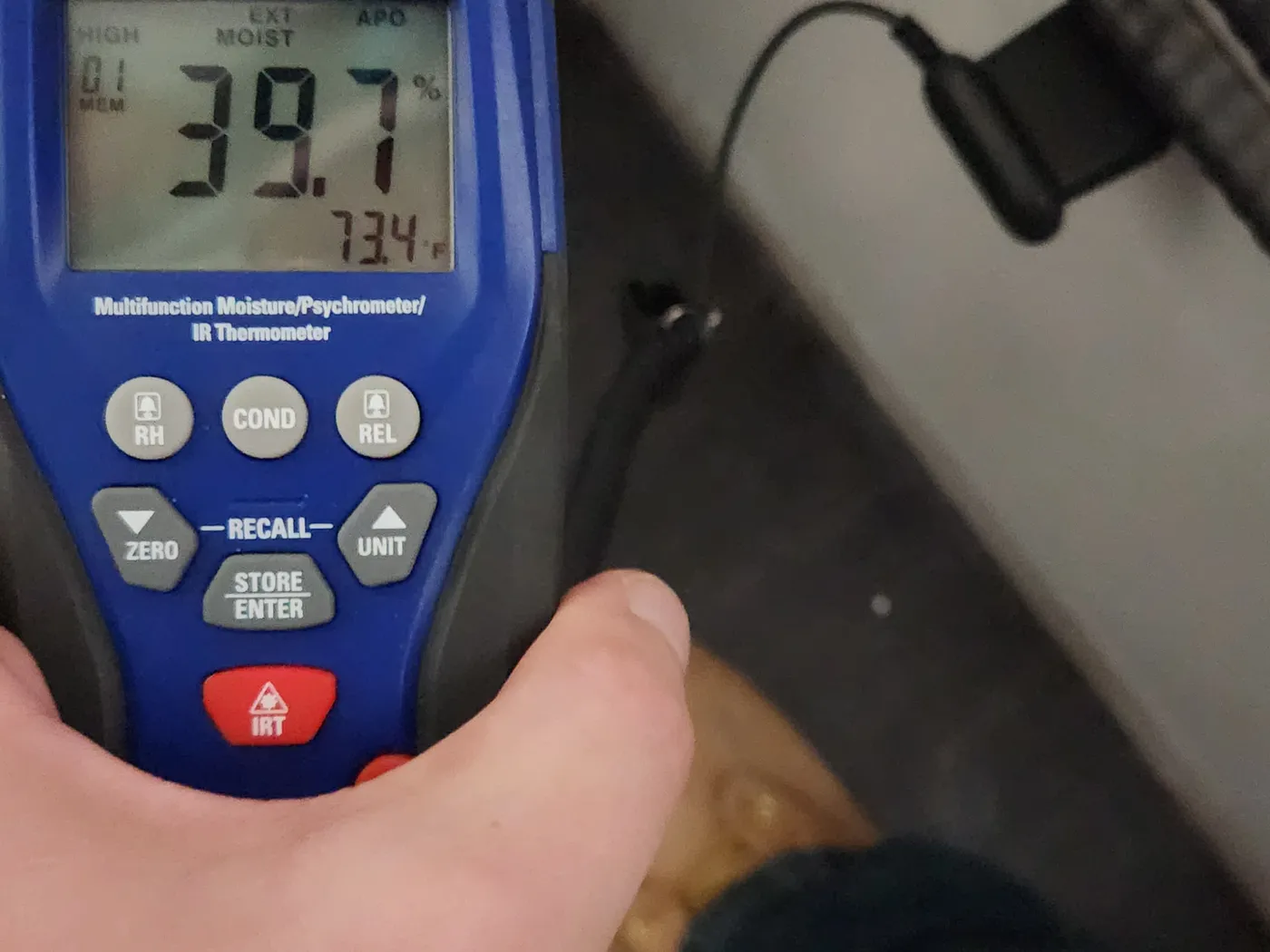 Handheld moisture meter and psychrometer reading 39.7 percent moisture content and 73.4 degrees Fahrenheit during a moisture survey.