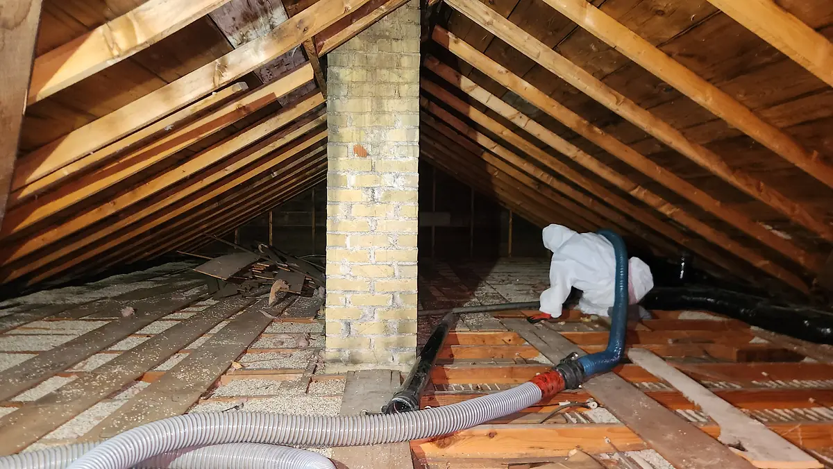 Technician removing insulation in an attic