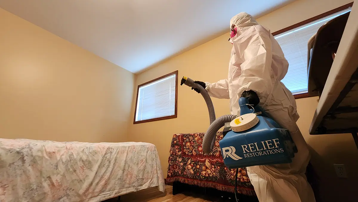 Technician applying deodorising fog in a bedroom with a ULV fogger