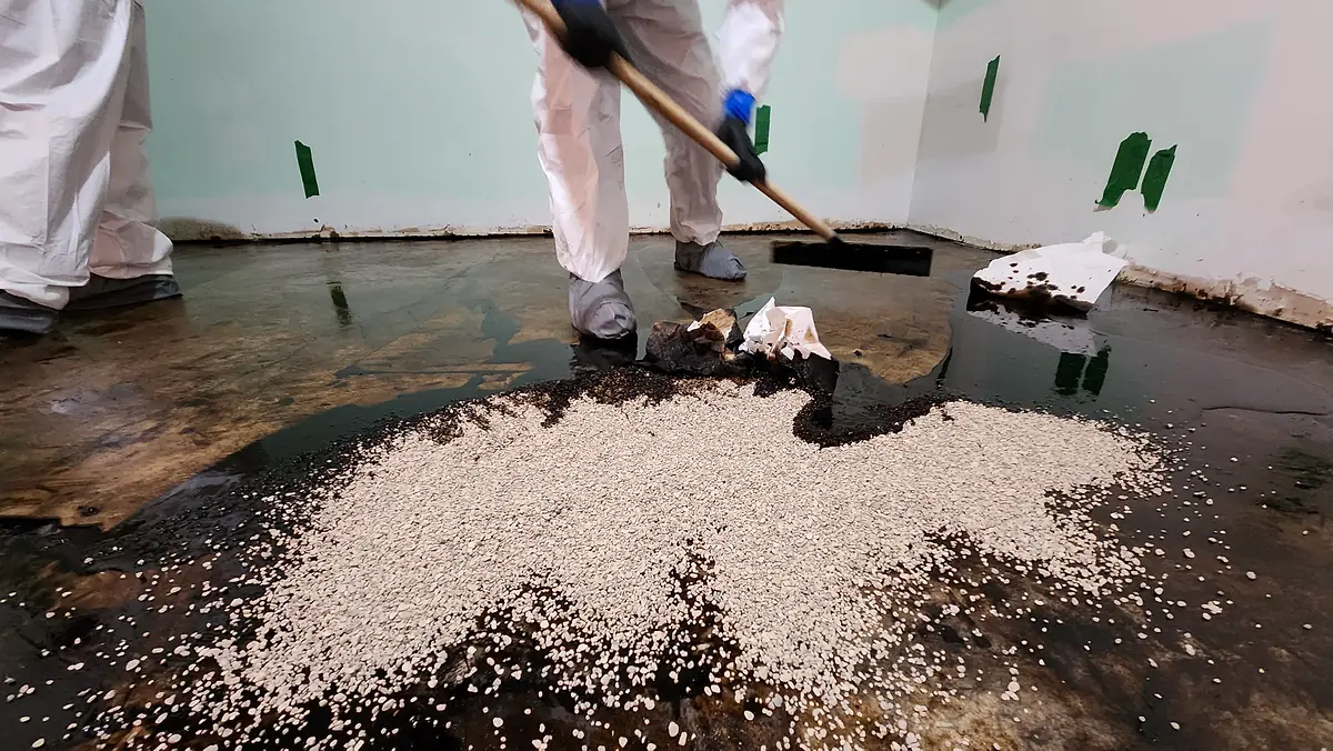 Technician removing vermiculite from a floor during abatement